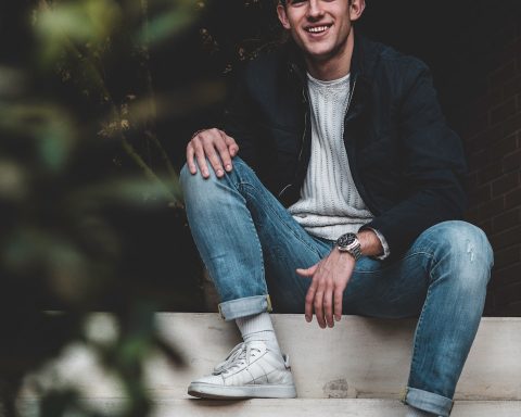 man in black jacket sitting on white concrete bench