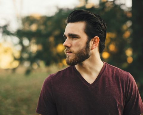 man wearing maroon V-neck t-shirt in forest