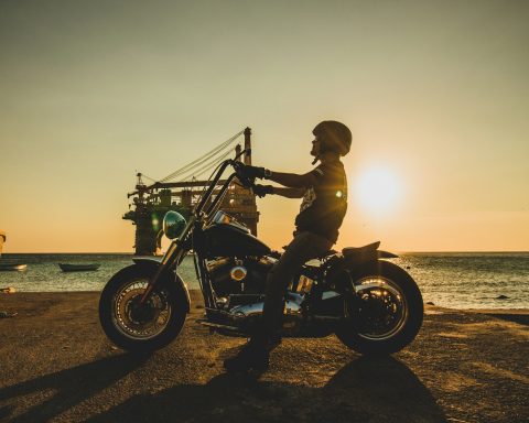 man riding motorcycle on beach during sunset