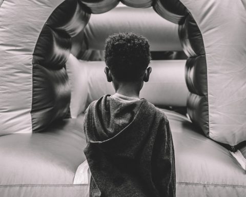 boy in gray sweater sitting on gray leather couch