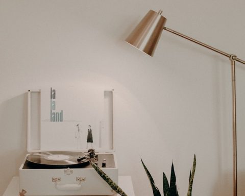 white turntable on white wooden organizer with vinyl record sleeves