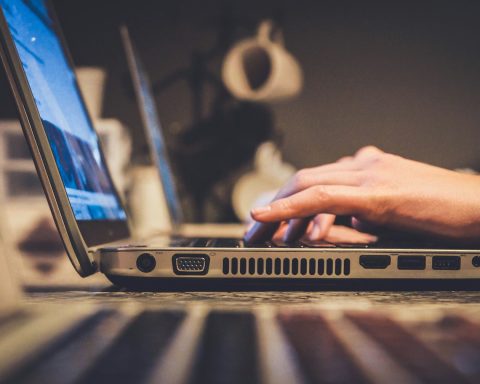 person using silver laptop computer on desk