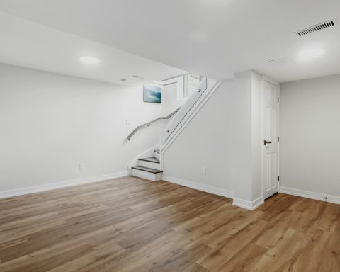 an empty room with a staircase and hard wood floors