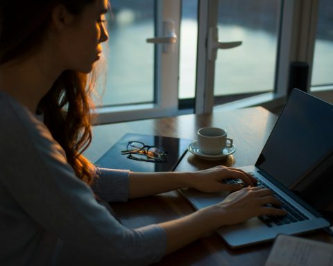 woman sitting beside table using laptop