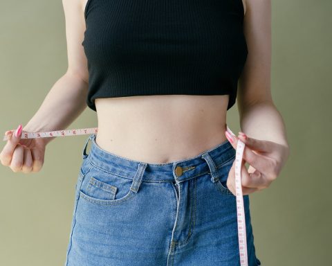 Een gespierde man die zijn tailleomtrek meet als alternatief voor BMI-meting