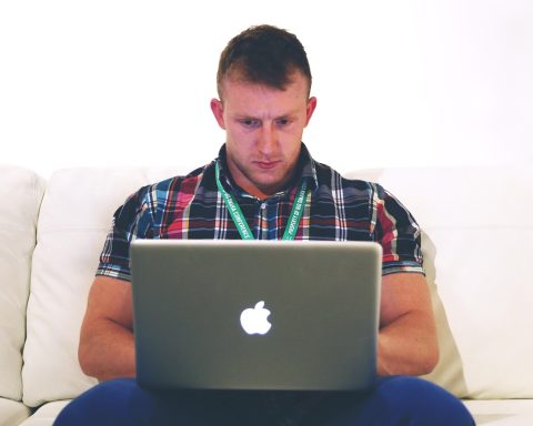 Man werkt geconcentreerd op laptop aan bureau thuis