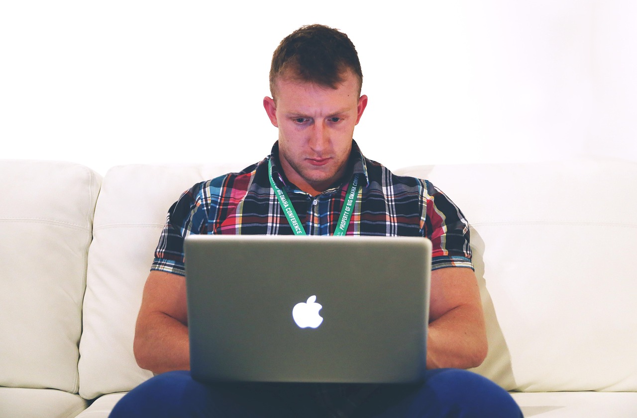Man werkt geconcentreerd op laptop aan bureau thuis