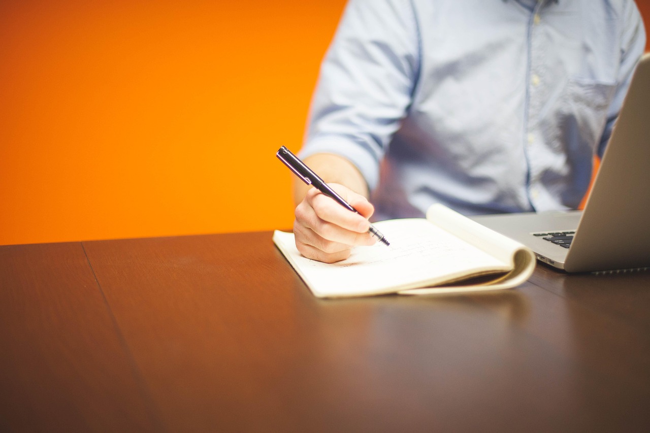 Zzp'er die zijn weekplanning bijhoudt in een notitieboek aan zijn bureau