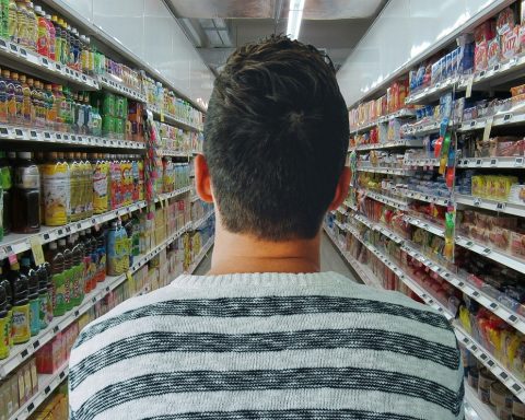 Man die boodschappen doet in de supermarkt met een boodschappenlijstje in zijn hand